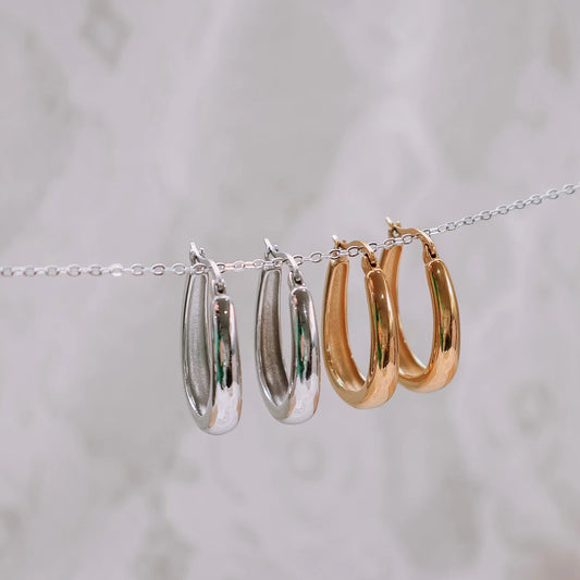 Maeve hoop earrings in silver and gold,  on a chain against a light background.