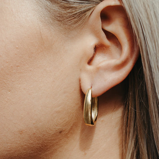 Gold hoop earring worn by a person with blonde hair.